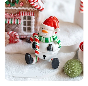 Detailed close-up of a resin snowman ornament with candy cane in a warm Christmas setting