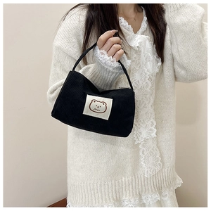 Close-up of black corduroy handbag featuring a cute cartoon bear patch detail