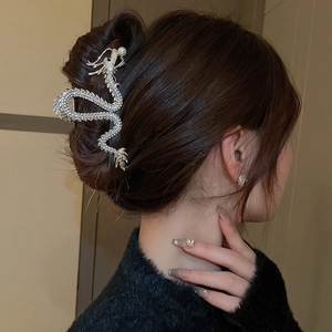 Silver dragon hair claw with rhinestones and pearl shown on a model's hairstyle