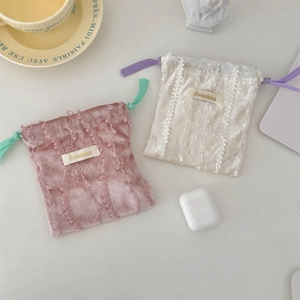Close-up of velvet drawstring pouch with lace trim and contrasting colorful ropes
