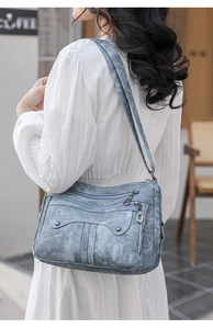Detail of light blue vintage crossbody bag with multi-zipper layers on model