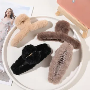 Close-up of four assorted plush hair claw clips in neutral tones on a white display tray