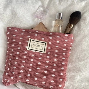 Pink pleated chiffon makeup bag with white dots and Pleasant Time label for travel storage