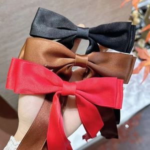 Close-up of elegant double-layered ribbon bow hair clips in black, brown and red satin