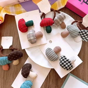 Handmade mushroom fabric hair accessories in various patterns on a warm wooden table