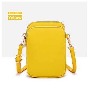 Detail view of mini yellow canvas phone bag with dual zippers and adjustable strap