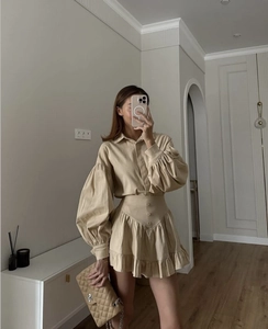 Detail of beige button-up shirt with lantern sleeves and tiered ruffle mini skirt