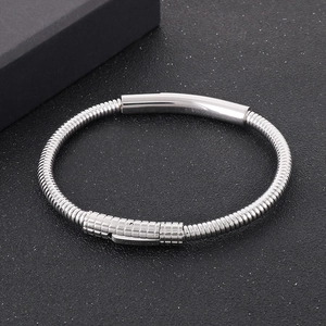 Detail of silver stainless steel snake chain bracelet with cylindrical clasp on dark texture