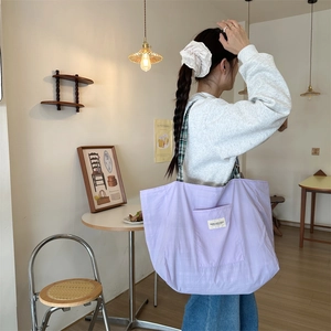 Detail of light purple canvas tote bag with woven label in a cozy cafe setting
