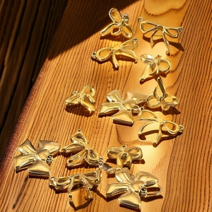 Macro detail of various gold-plated bow pendants on a textured wooden background