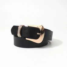 Close-up of thin black PU leather belt with gold metal buckle and sparkling rhinestone detail