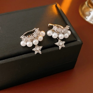 Detail shot of silver double-layer earrings with pearls, zircons, and star pendants