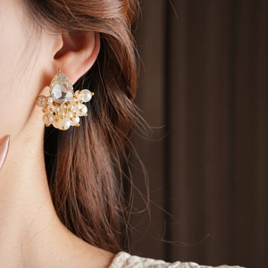 Close-up of a teardrop crystal stud earring with white pearls on a gold-tone base