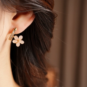 Macro side view of elegant pink resin flower earrings with sparkling zircon on a gold base