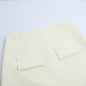 Detailed macro view of beige pencil skirt waistline featuring symmetric patch pocket design