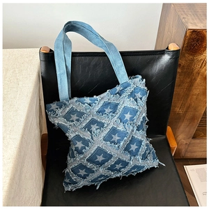 Macro detail of fringed denim tote bag with star patterns on a leather chair
