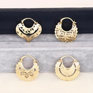Detailed macro view of four vintage golden hollow earrings with floral engraving