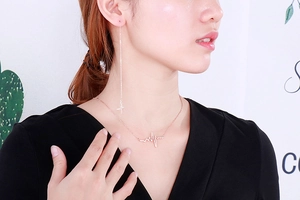 Close-up of rose gold ECG necklace and earrings set worn by model in soft lighting