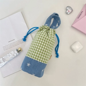 Flat lay of checkered drawstring water bottle bag with star patterns and lifestyle props