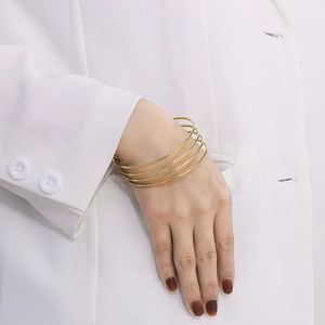 Detail view of a multi-layer gold stainless steel spring bracelet on a female wrist