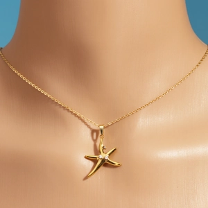 Detail of gold starfish pendant with pearls and rhinestones on woman's neck