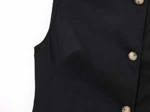 Detail of linen blend vest showing black fabric texture and amber resin button