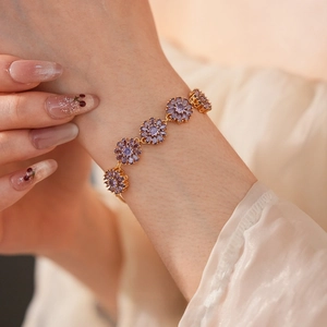 Close-up of gold plated floral bracelet with purple zircon petals on model wrist