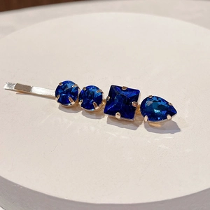 Detailed macro of gold hair clip featuring prong-set deep blue multifaceted rhinestones