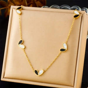 Collier en acier inoxydable doré avec pendentifs cœurs noirs et blancs sur écrin