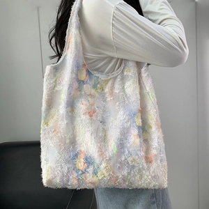 Détail de broderie florale et texture de franges sur un grand cabas blanc en toile