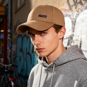 Brown winter baseball cap with blue AHYT embroidery worn by male model in street style