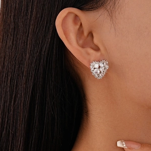 Close-up of a model wearing a delicate silver heart-shaped stud earring with cubic zirconia