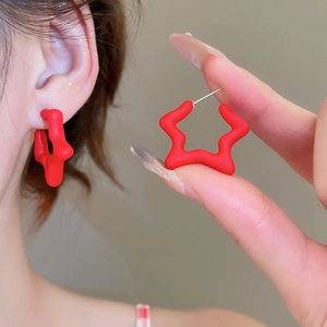 Detail view of a matte red star earring worn on the ear featuring a sleek resin design