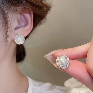 Close-up of pearl stud earrings with zircon halo and gold-plated silver needle detail