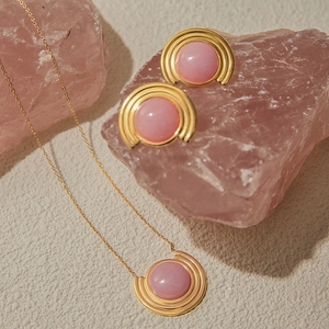 Gros plan sur l'ensemble collier et boucles d'oreilles en titane avec pierres roses