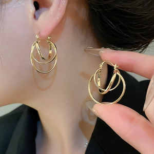 Detail of gold multi-layered circular earrings showing polished finish on a model
