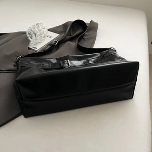 Détail du cabas minimaliste en cuir PU noir avec bandoulière large et boucle en métal