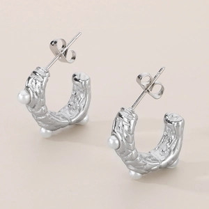 Macro shot of silver C-hoop earrings featuring hammered texture and inlaid pearls