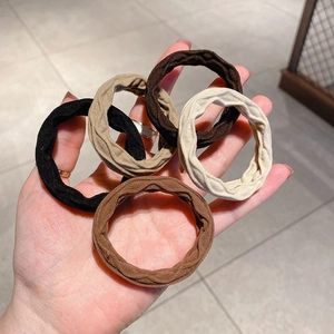 Detail von fünf hochelastischen Haargummis in neutralen Erdtönen in der Hand gehalten