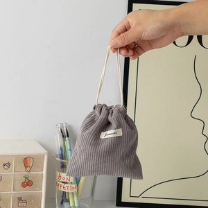 Detail of grey corduroy drawstring pouch with brand label shown held in hand