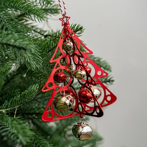 Red Christmas tree bell pendant with metal cut-out frame hanging on a green tree