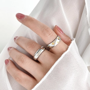 Detail of two-tone titanium steel rings with star patterns worn on hand over white fabric