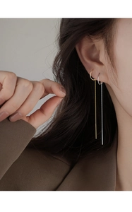 Detail shot of long minimalist gold and silver streamlined tassel earrings on a model