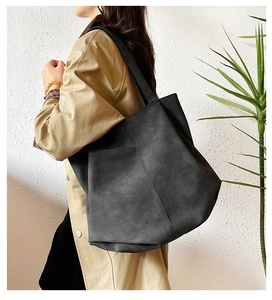 Detail of a large dark grey tote bag in matte suede leather with vertical stitching