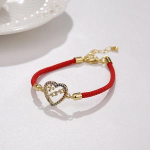 Detail of red braided MAMA bracelet with gold heart pendant and colorful cubic zirconia