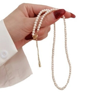 Elegant white pearl necklace with adjustable gold chain held by a hand on white background
