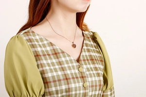 Close-up of rose gold heart pendant necklace for women worn by a model