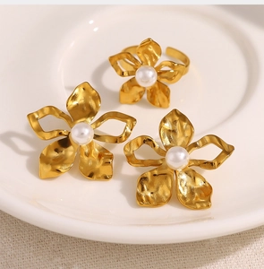 Detailed macro of gold flower jewelry set with pearls on a white ceramic plate