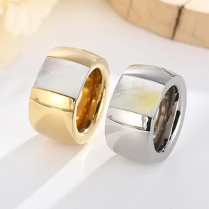 Detailed view of wide titanium steel rings featuring mother of pearl inlays on a light surface