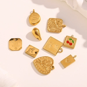 Detailed view of 9 unique 18K gold plated stainless steel pendants on white surface